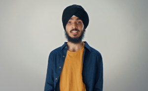 Young Sikh man wearing a black turban and a blue shirt over an orange t-shirt